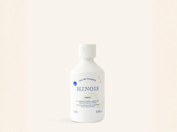 Eau nettoyante Minois Paris pour visage et corps, nettoyage sans rinçage, flacon transparent avec logo blanc.